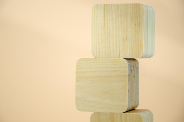 I cubi di legno vuoti sono impilati a forma di torre, uno sopra l'altro. i blocchi sono allineati verticalmente su fondo beige. concetto di business, interazione, crescita. modello per il design, spazio per il testo