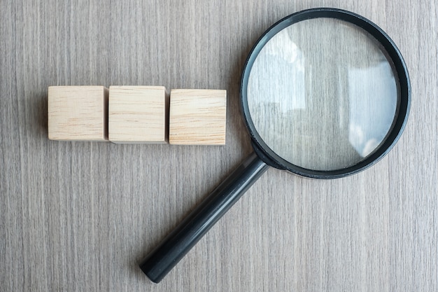 Empty wooden cubes and magnifying glass on wood table 