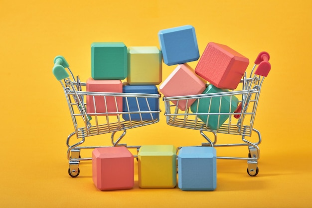 Empty wooden cubes mockup style, copy space with shopping trolleys on yellow background. colourful blocks template for creative design, place for text