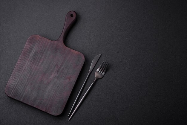 Empty wooden cutting board on dark textured concrete background