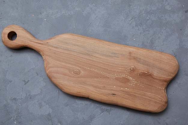Empty wooden cutting board lies on a gray background. Template for food photography.