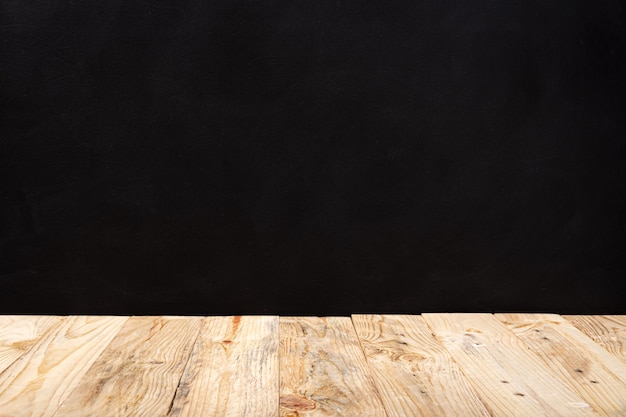 Empty wooden deck table over black wall