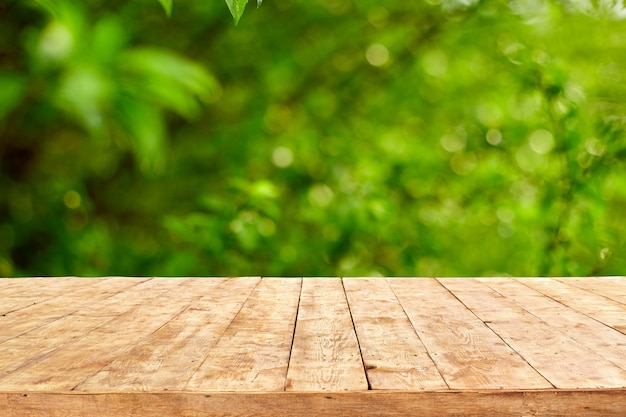 Empty wooden deck table with foliage bokeh background.