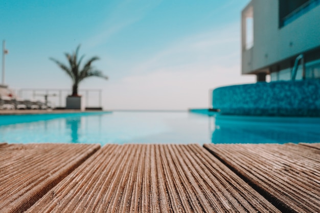 Foto piattaforma di legno vuota con piscina, bella vista laterale della piscina minimalista con cielo azzurro chiaro. applicare il colore del filtro vintage