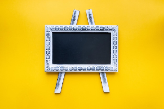 Empty wooden frame chalkboard on yellow background