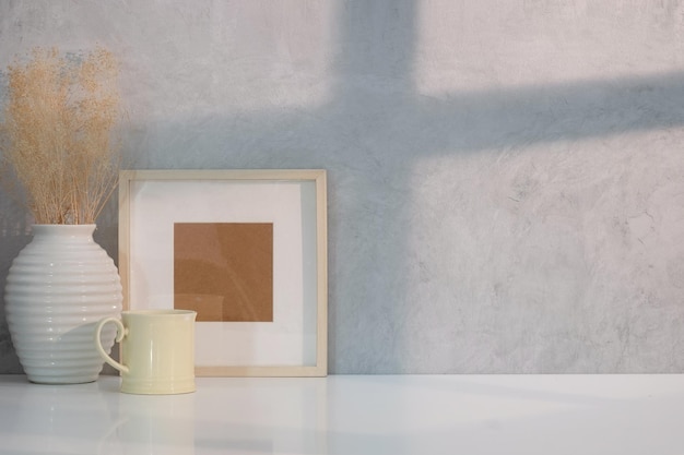 Empty wooden picture frame coffee cup and plant on white table