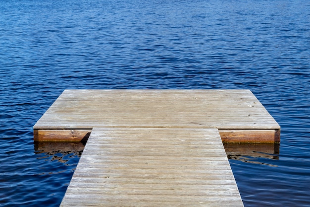 Empty wooden pier and blue water surface with small waves.