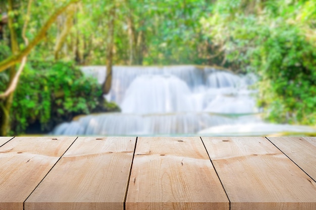 写真 ぼやけた滝の背景に製品を置くためのビンテージ スタイルの空の木の板の長いテーブル トップ