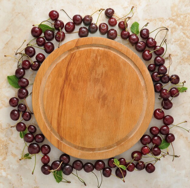 Empty wooden plate and scattered around it cherries