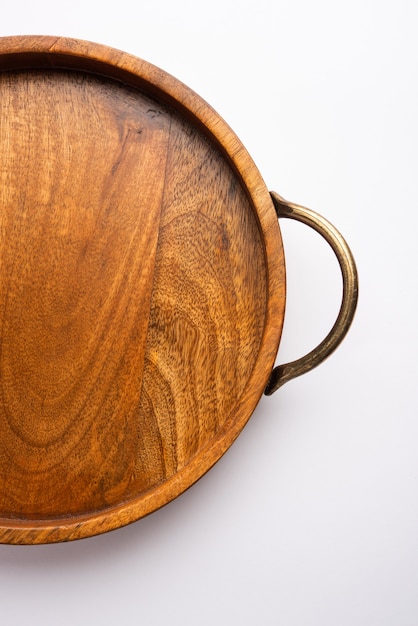 Empty wooden round tray with brass handle on white surface