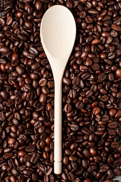 Empty wooden spoon on a coffee beans background. Top view.