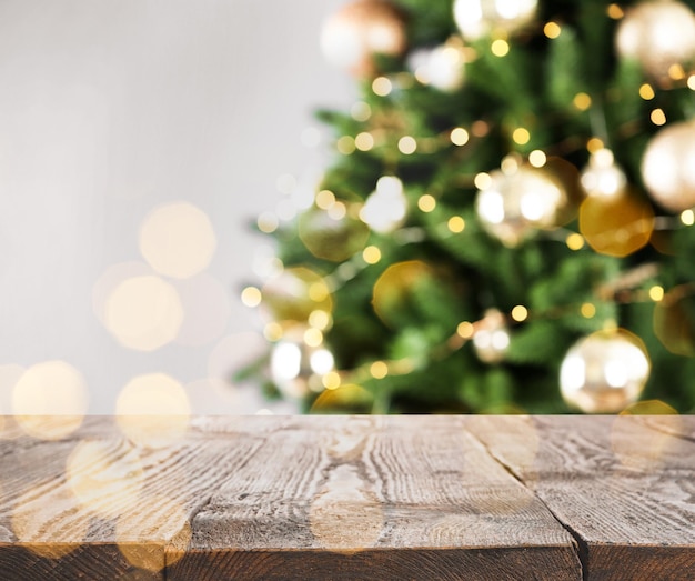 Empty wooden surface and blurred Christmas tree on background bokeh effect Space for design