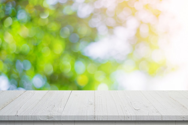 Svuoti la tavola di legno e il bokeh verde vago estratto lascia la struttura del fondo, montaggio dell'esposizione con lo spazio della copia.