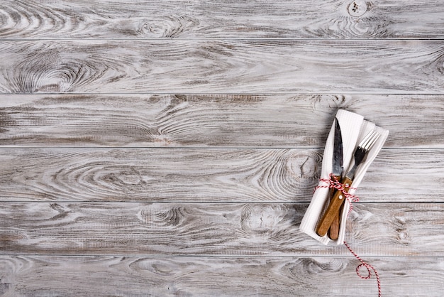 Empty wooden table background and fork and knife on napkin. Dinner, lunch or breackfast concept.