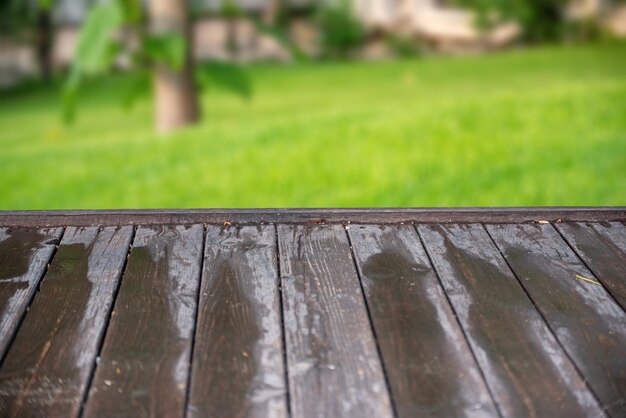 Empty wooden table background with defocused blurred green lawn natural outdoor concept