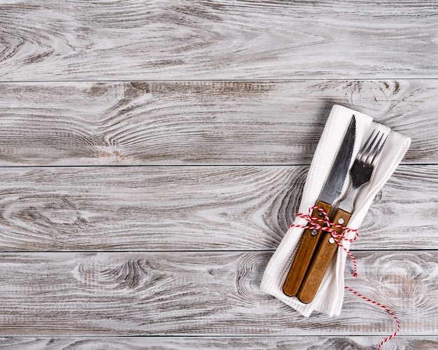 Empty wooden table and fork and knife on napkin.
