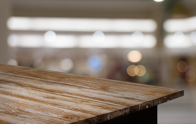 커피의 추상적인 흐릿한 배경 앞에 있는 빈 나무 테이블은 제품을 전시하거나 조립하는 데 사용될 수 있습니다.
