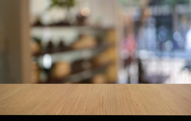 커피숍의 추상적인 흐릿한 배경 앞에 있는 빈 나무 테이블은 제품을 표시하거나 몽타주하는 데 사용할 수 있습니다. 제품 표시를 위해 Mock up