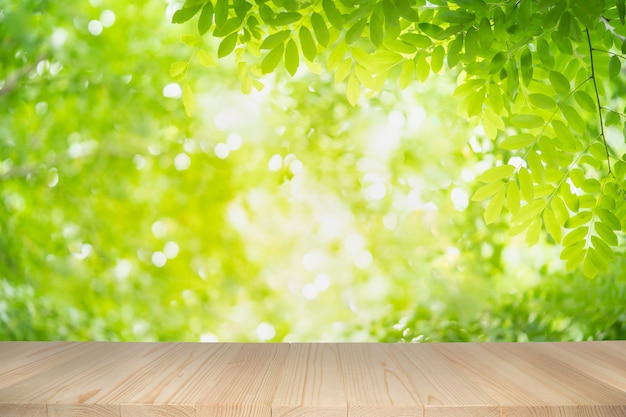 Empty wooden table on green nature background with beauty bokeh under sunlight.