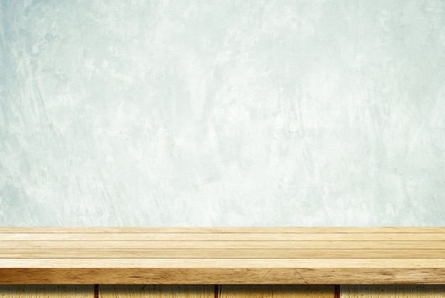 Empty wooden table over grunge cement wall background