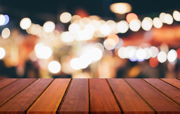 光スポットとボケ味を持つ抽象ぼやけお祝い光背景の前に空の木製テーブル