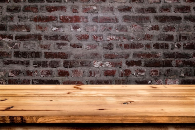 Empty wooden table for product placement or montage with focus to the table top brickwall background