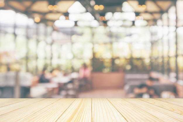 Photo empty wooden table top with cafe restaurant coffee shop interior abstract blur defocused with bokeh light background for montage product display