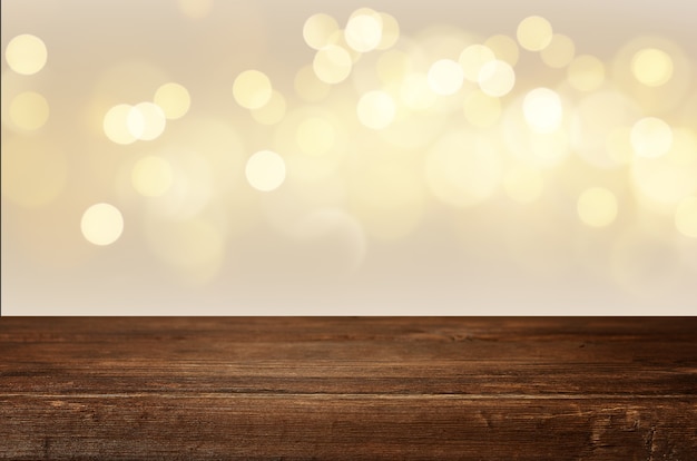 Empty wooden table with Christmas lights in the background