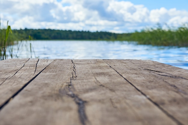 Empty wooden table with landscape background. Lake with mist and cloud. Focus on wooden desk table.