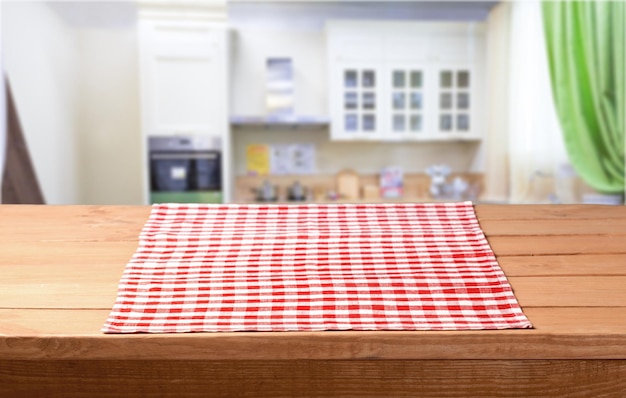 Empty wooden table with tablecloth over bokeh kitchen background