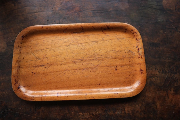 An empty wooden tray placed on a old grunge dark textured wooden table background