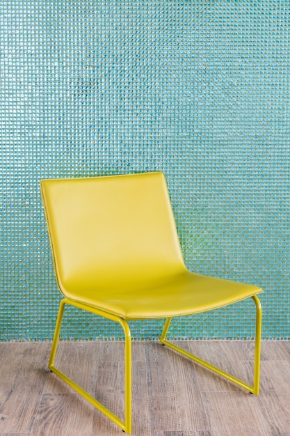 Foto sedia gialla vuota sul muro di piastrelle blu