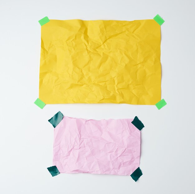 Empty yellow and pink crumpled sheets of paper glued with green sticky pieces