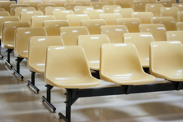 Empty yellow plastic chairs in many rows