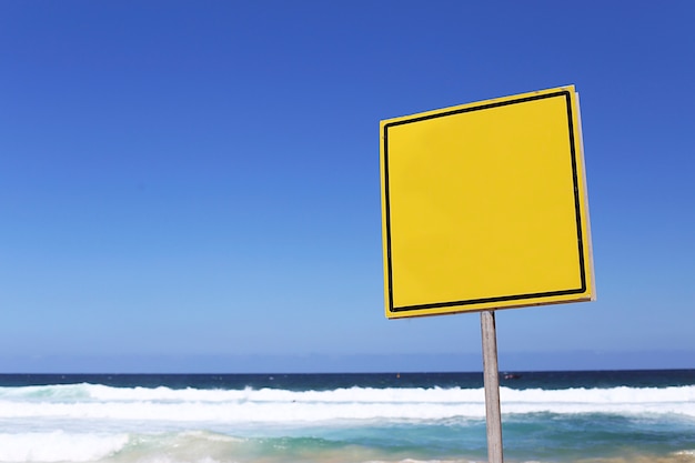 Empty yellow sign on the beach at sunny day