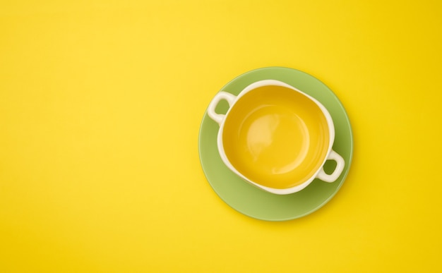 Empty yellow soup plate on a yellow bacground, top view