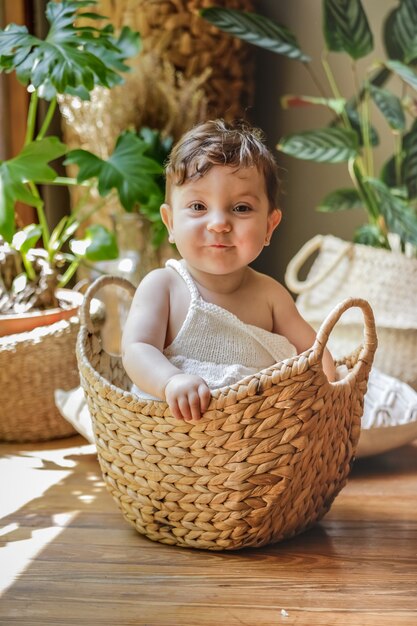 Één éénjarige baby die en binnen een mand glimlacht stelt