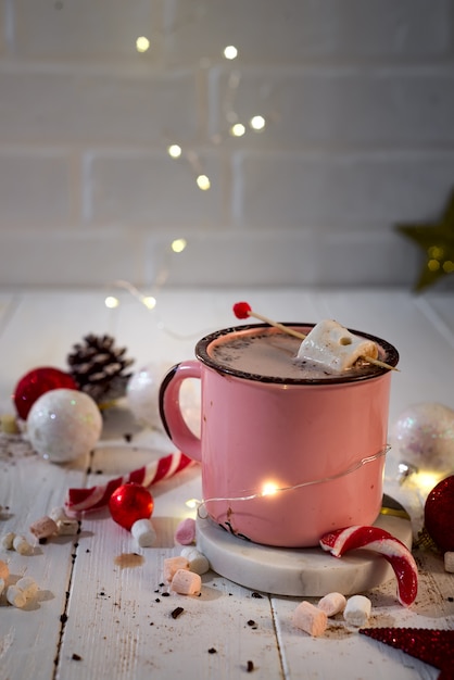 Enamel cup of hot cocoa with mini marshmallows and candy canes