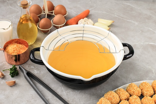 Enamel deep fried pan with stainless rack, preparing cooking nugget/arancini in the kitchen