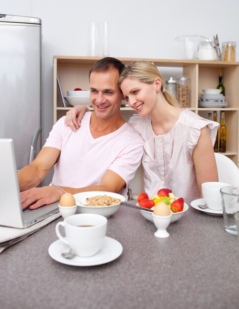 Enamored couple using a laptop while having breakfast 