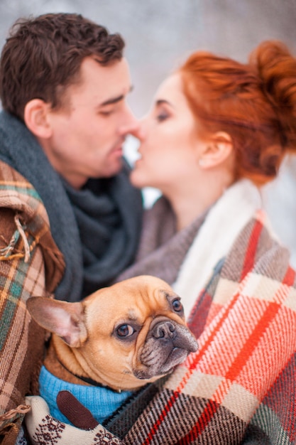 Enamoured tender couple in warm clothes with french bulldog, closeup