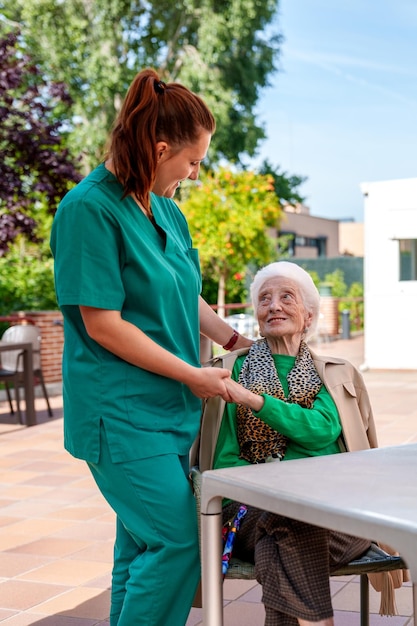 Endearing Care Elderly Woman Embraces Sunny Serenity Guided by Loving Nurse in Elderly Care Facility