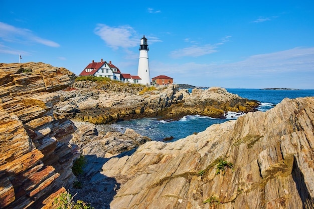 Endless rocky coastline with large white lighthouse in Maine