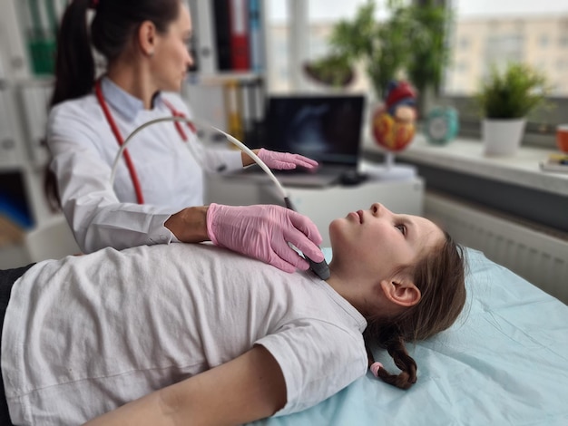 Endocrinologist doctor makes ultrasound of thyroid gland to girl child in clinic