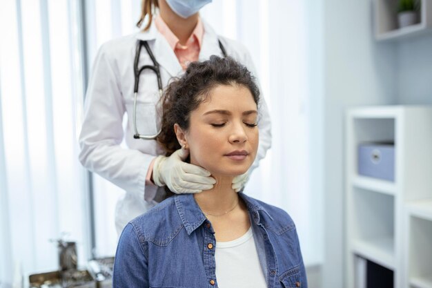 内分泌科医が若い女性の喉を診療所で検査する 女性 甲状腺検査 内分泌学ホルモンと治療 喉の痛みの炎症