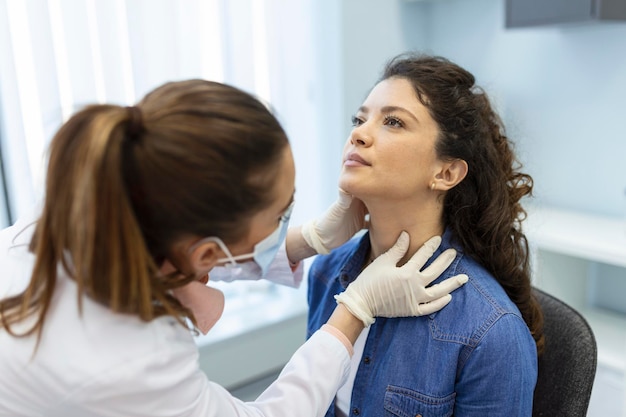 Foto endocrinologo che esamina la gola di una giovane donna in clinica donne con test della tiroide ormoni endocrinologici e trattamento infiammazione del mal di gola