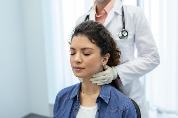 Endocrinoloog die keel van jonge vrouw in kliniek onderzoekt Vrouwen met schildkliertest Endocrinologische hormonen en behandeling Ontsteking van de zere keel