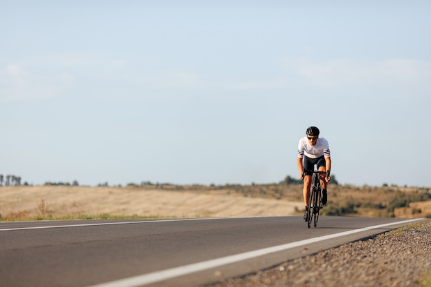 Enduring young man in protective helmet practising in cycling during morning time