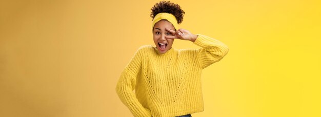 Photo energetic charming millennial africanamerican female student in yellow sweater headband show victory