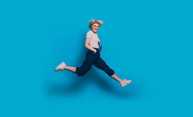 Energetic charming woman with blonde hair smiling  and jumping